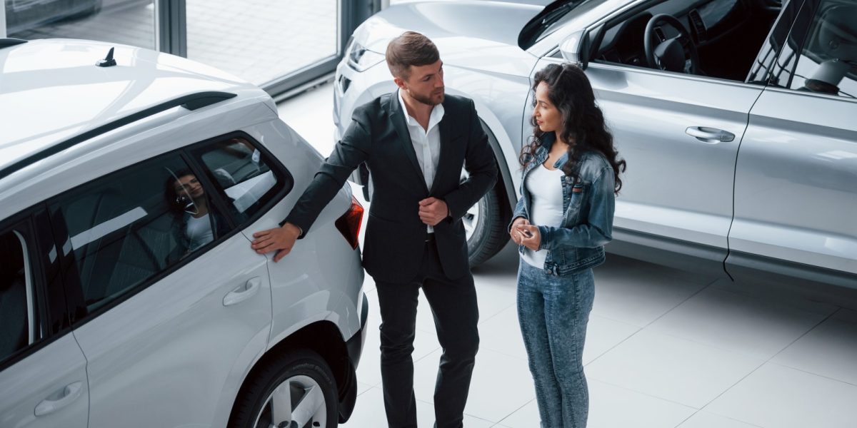 Perfect choise. Female customer and modern stylish bearded businessman in the automobile saloon.