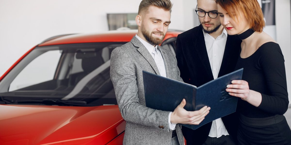 Couple in a car salon. Family buying the car. Elegant woman with her husband. Assistant with a clients