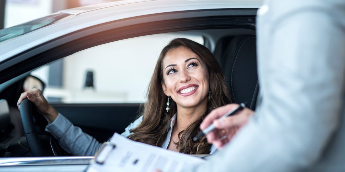 Happy customer buying brand new car at local car dealership.