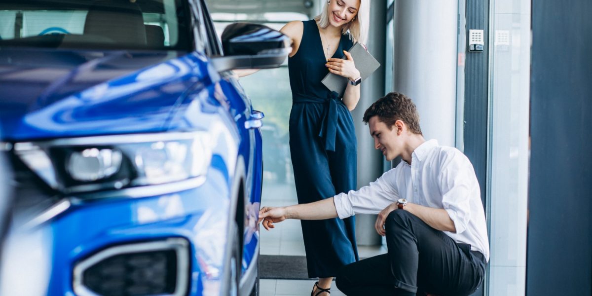 Young handsome man choosing a car in a car showroom