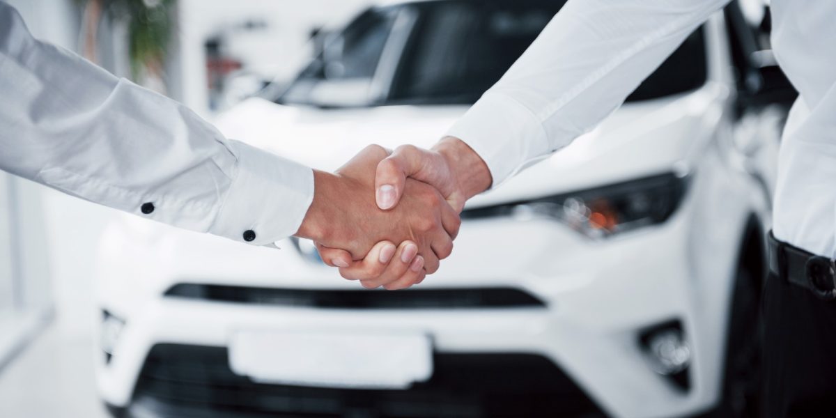 Close up of sales manager in black suit selling the car to the customer.